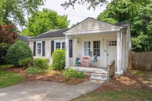 A single-story house with a front porch, a small garden, and a wooden fence.