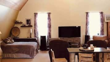 Cozy loft-style accommodation with a comfortable bed, sofa, and dining area.