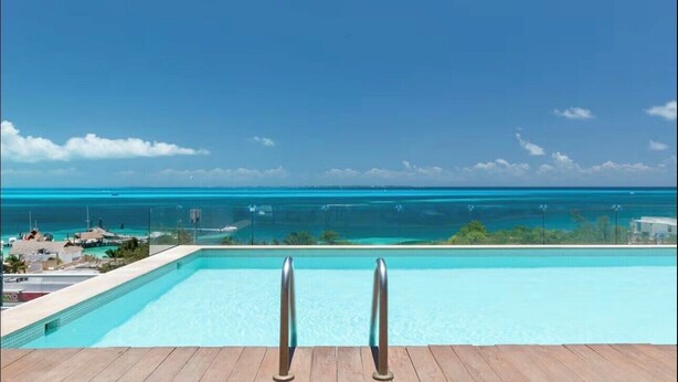 Una piscina con vista al océano y un cielo despejado.