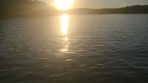 Ein ruhiger See, die Sonne spiegelt sich auf der Wasseroberfläche.