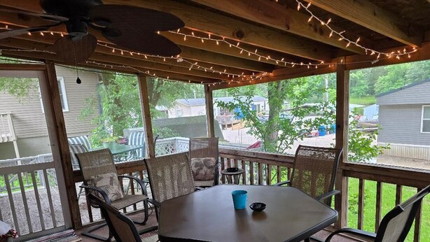 Eine überdachte Terrasse mit Tisch und Stühlen, Lichterketten und Blick auf den Garten.