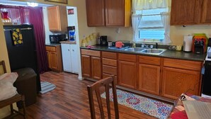 Eine kompakte Küche mit Holzausstattung, inklusive Kühlschrank, Mikrowelle und Spüle.