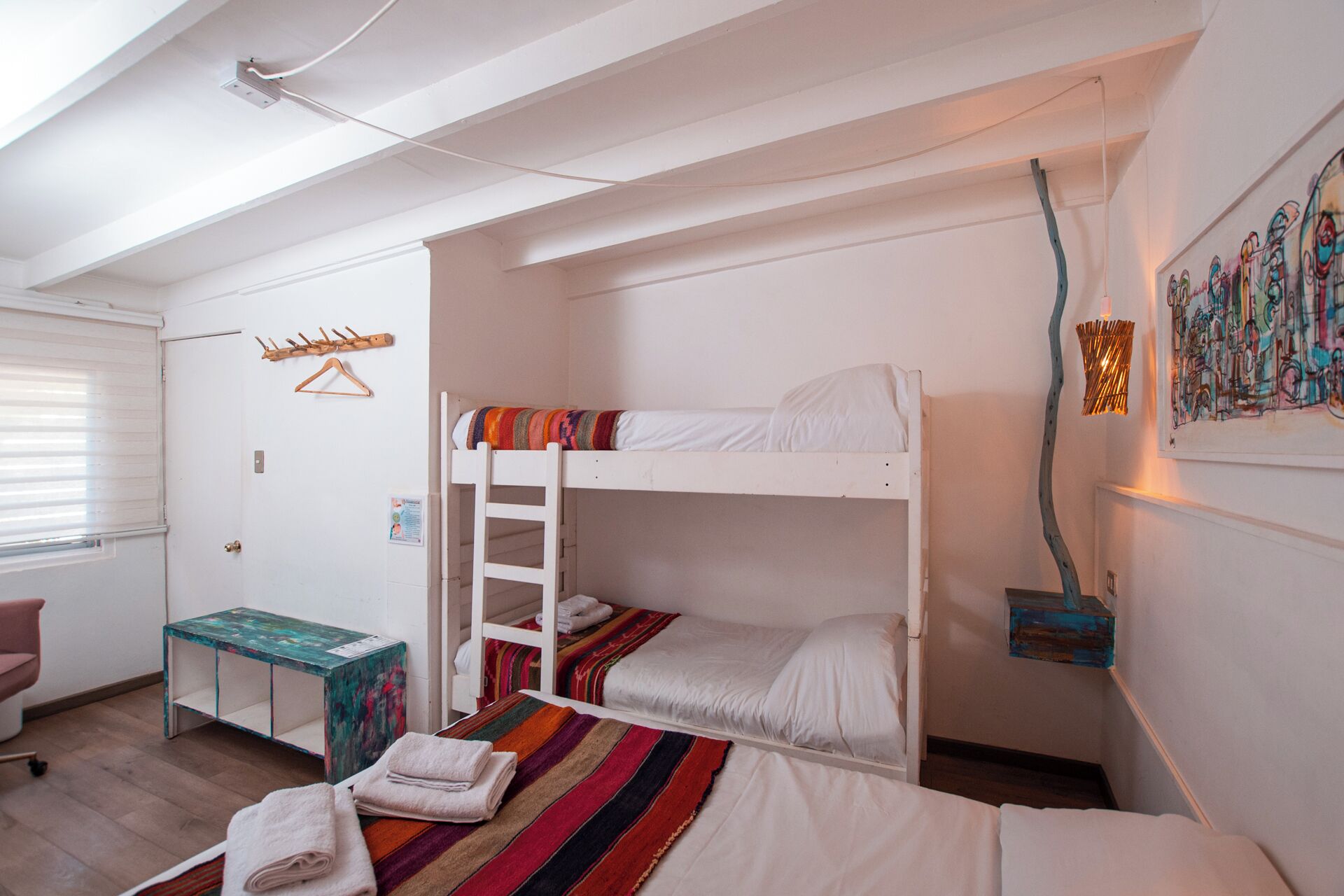 A bunk bed room with a desk and a painting on the wall.