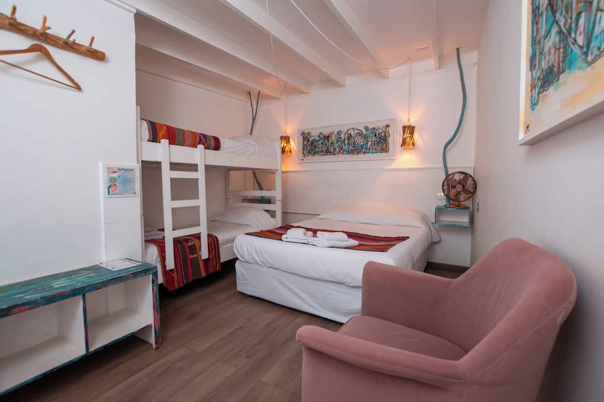 Habitación con literas, escritorio, silla y ventilador de pared.