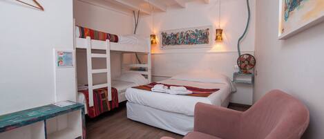 A bunk bed room with a desk, a chair, and a wall-mounted fan.