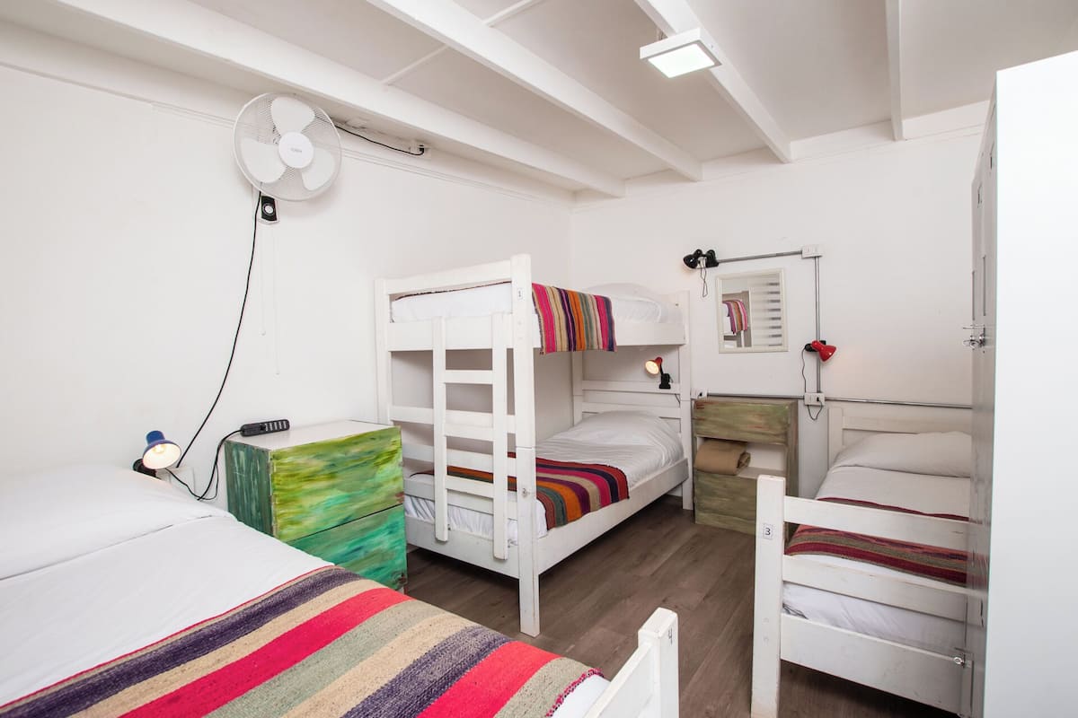 Un dormitorio con literas, un escritorio con lámpara y un ventilador en el techo.
