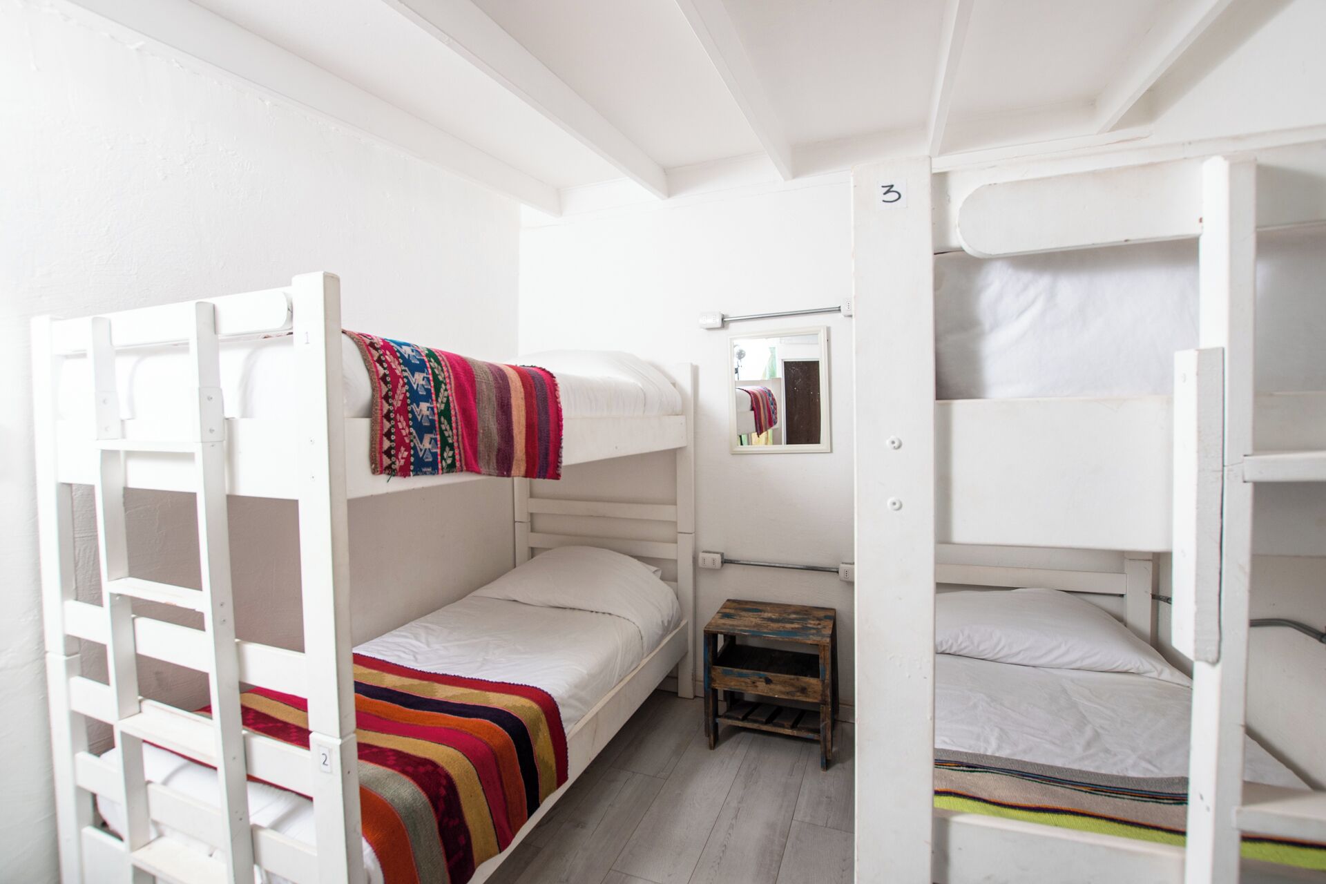 Habitación con literas, una mesita pequeña y un espejo.