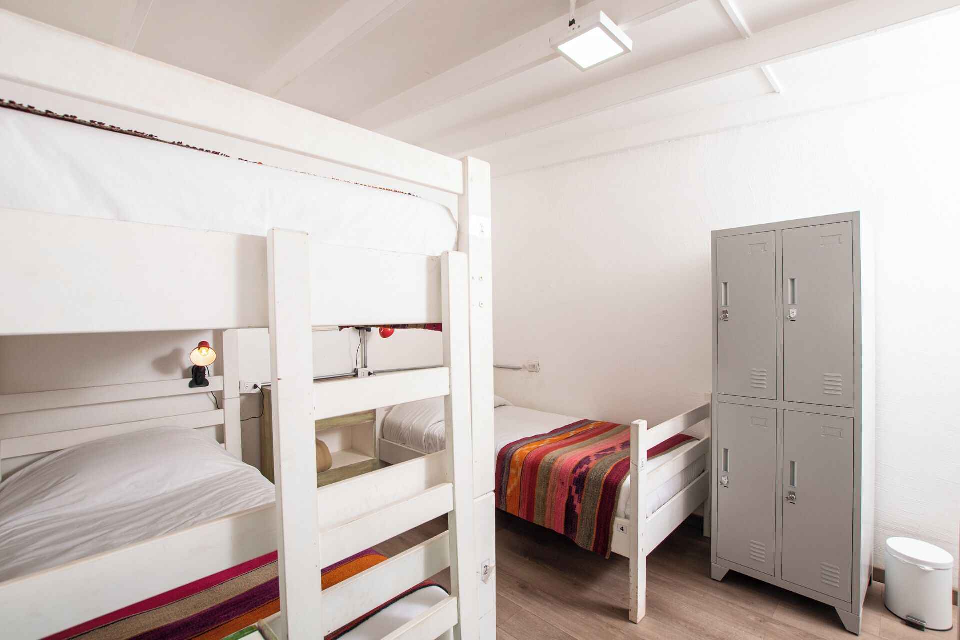 Habitación con literas, un escritorio, un armario y un pequeño cubo de basura.