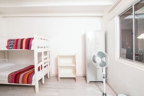 A room with bunk beds, a wardrobe, a fan, and a window. - Hostal Copart (San Pedro de Atacama)