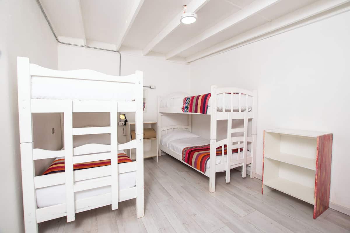 Una habitación con dos literas, un escritorio y un estante.