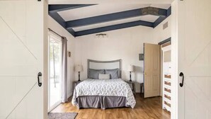 A bedroom with a bed, bedside tables, and a wooden floor. - Black Bear Suite/Hot Tub/Sleeps 4/affordable! (Oakhurst)
