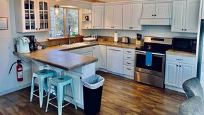 A kitchen with white cabinets, a stainless steel oven, and a wooden island with stools. - Black Bear Suite/Hot Tub/Sleeps 4/affordable! (Oakhurst)
