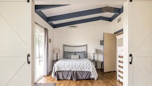 Une chambre à coucher comprenant un lit, des tables de chevet et une porte avec un meuble de rangement intégré.