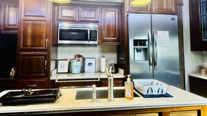 A modern kitchen with wooden cabinets, stainless steel appliances, pendant lighting, and a stainless steel refrigerator. - Happy Hedgehog - River Views - Hot Tub - Private (Ahwahnee)