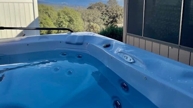 Un jacuzzi con vistas despejadas a los árboles circundantes y un edificio al fondo.
