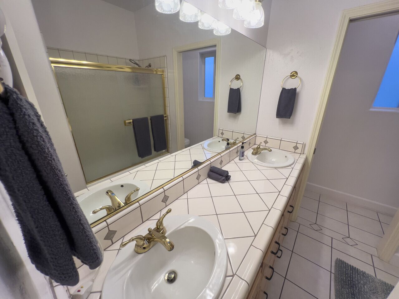 A bathroom with two sinks, a large mirror, and a shower area.