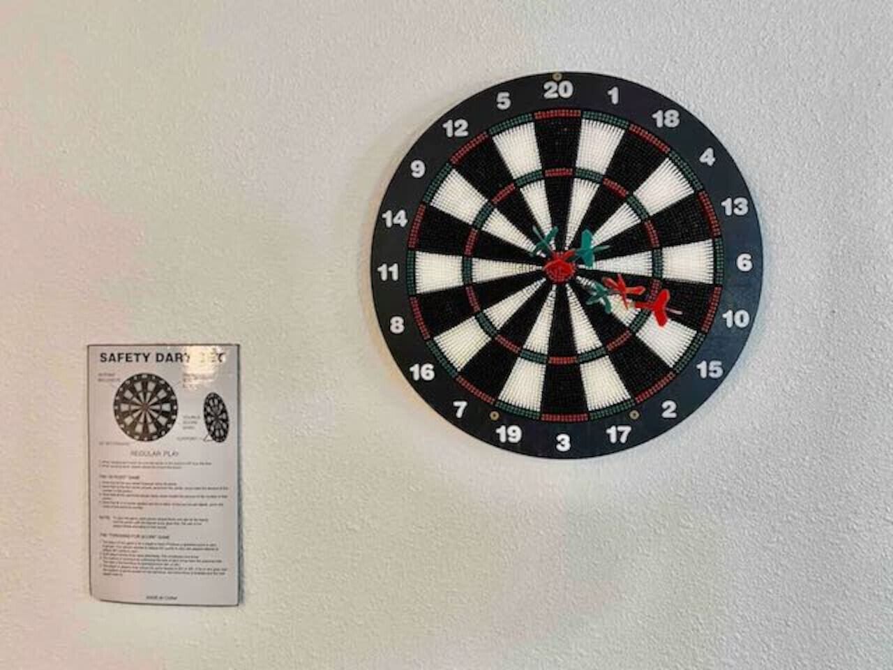 Dartbord bevestigd aan een muur met een veiligheidsbericht ernaast.