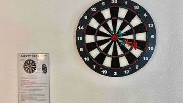 Dartbord bevestigd aan een muur met een veiligheidsbericht ernaast.