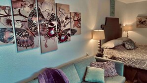 Un dormitorio con cama, sofá y un cuadro de mariposas en la pared.