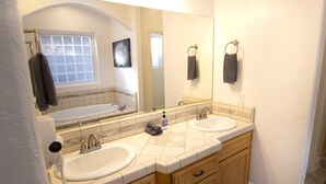 Un baño con dos lavamanos, un espejo grande y una ventana.