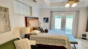Una habitación de hotel con una cama, un sofá verde, una mesita, una lámpara y un ventilador de techo.