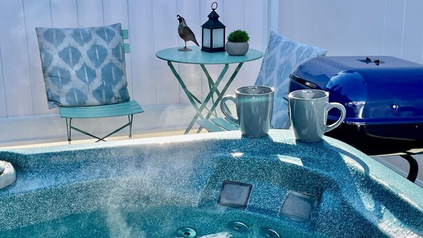 Een hottub met een klein tafeltje en stoelen in de buurt, een lantaarn en een barbecue.
