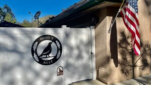 Een poort met een logo met daarin een vogel en de tekst 'Quail's Nest'.