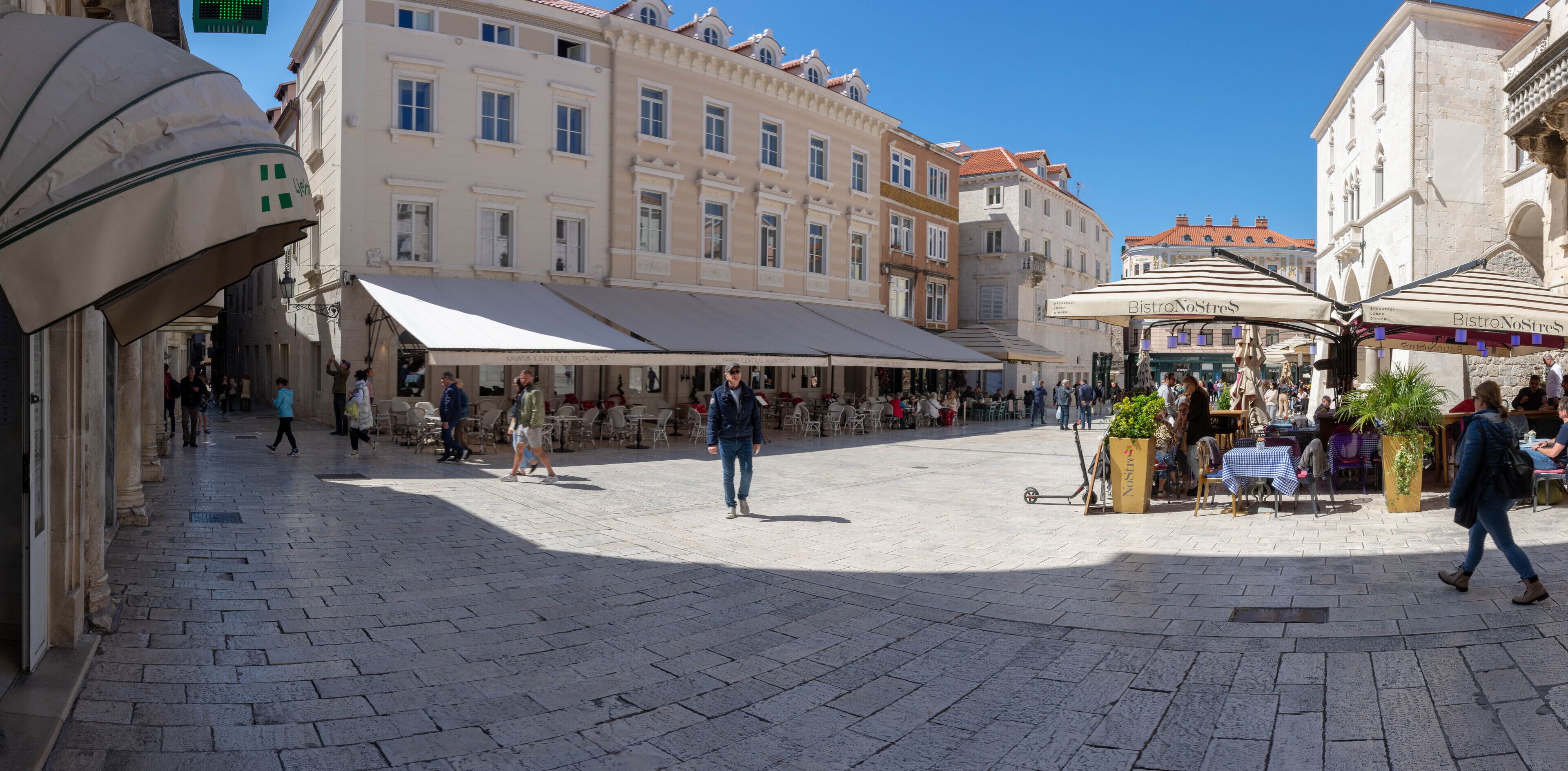 A public square with outdoor seating areas and cafes, surrounded by historic buildings.
