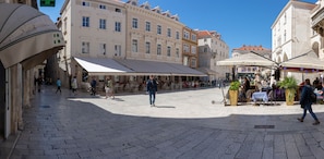 Una plaza pública con zonas de estar al aire libre y cafés, rodeada de edificios históricos.