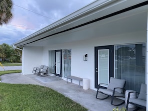 Uma casa moderna com varanda coberta, portas de correr deslizantes e área de estar externa.