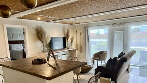 Et moderne opholdsrum med en central ø, en sofa og et fjernsyn.