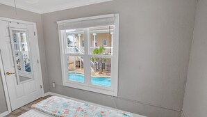 Een slaapkamer met een groot raam, een deur en een bed met een bloemenprint.