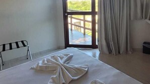 Une chambre d’hôtel avec un lit, une fenêtre avec des rideaux, un appareil de climatisation et une vue sur l’extérieur.