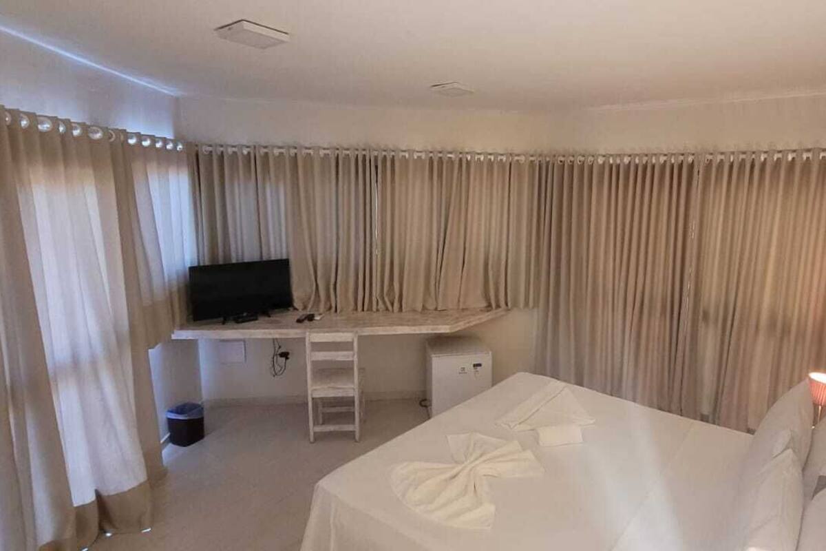 Una habitación de hotel con una cama, un escritorio con ordenador y cortinas.