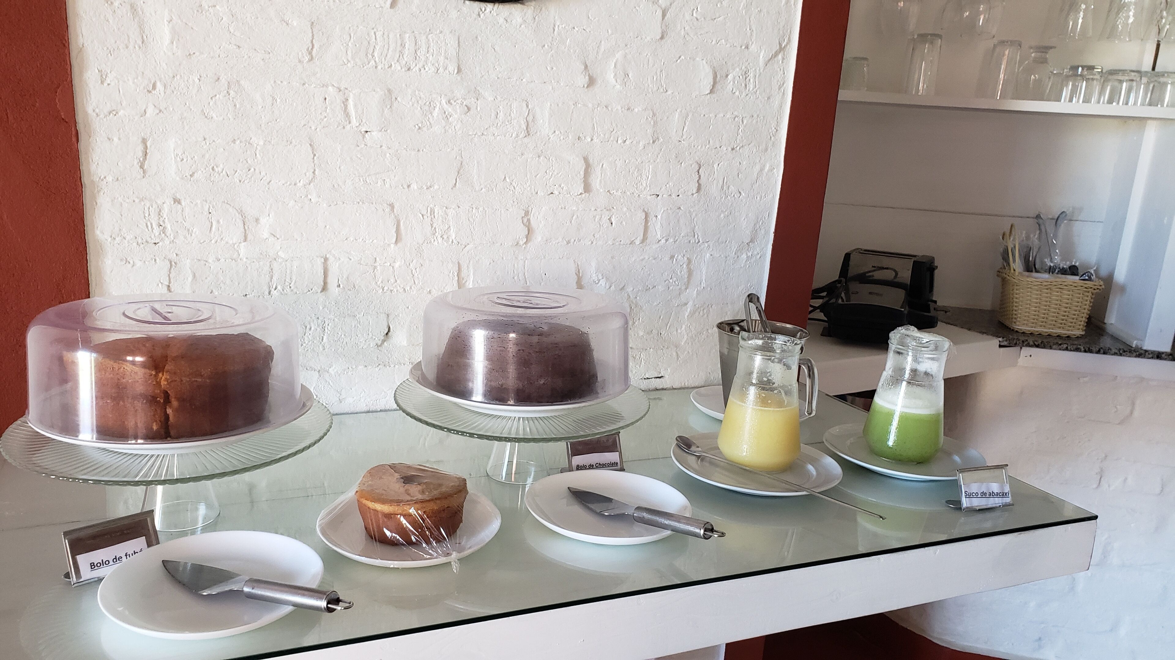 A buffet table with various food items including a chocolate cake, a green drink, and a plate with a knife.