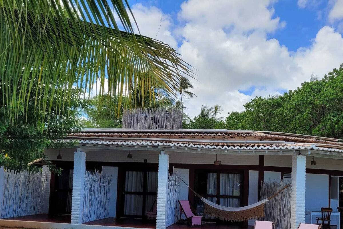 Una casa con piscina, terraza techada y una hamaca.