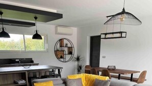 Ein modernes Wohnzimmer mit einem grauen Sofa, zwei runden Tischen und einer gelben Decke.