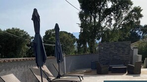 Ein Poolbereich mit Liegestühlen und Sonnenschirmen, eine Steinmauer und ein klares, blaues Schwimmbecken.