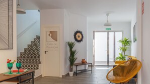 Un moderno vestíbulo de hotel con una escalera, un mostrador de recepción, una silla amarilla y una puerta con la señalización 