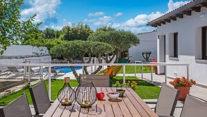 Una terraza de madera con una mesa, sillas y candelabros de vidrio decorativos.