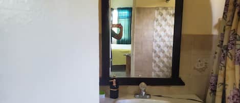 A bathroom with a white sink, a mirror, and a shower curtain.