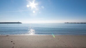 Ein Strand mit blauem Himmel, ruhiger See und fernen Leuchttürmen.