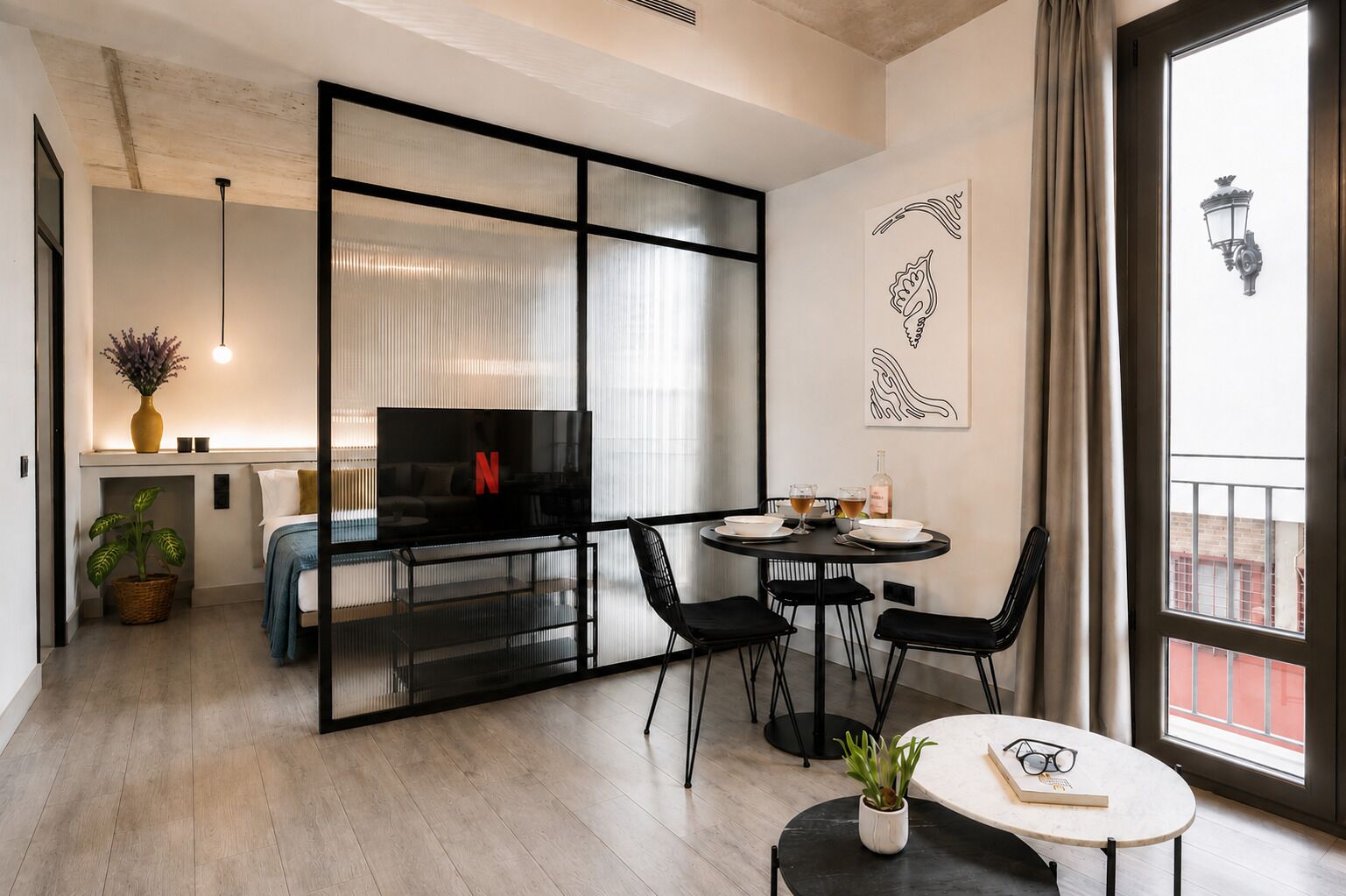 A modern living room with a TV, a dining area with chairs, a small table with a plant, and a large window with a view.