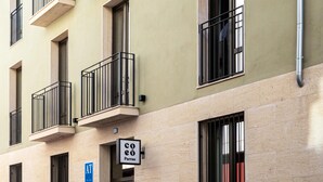 Un edificio de varios pisos con balcones, una entrada visible y un letrero que indica una cafetería.