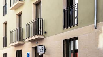 Un edificio de varios pisos con balcones, una entrada visible y un letrero que indica una cafetería.