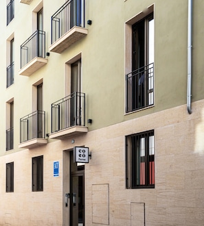 A multi-story building with balconies, a visible entrance, and a sign indicating a cafe.
