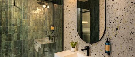 A bathroom with a shower, a sink, and a mirror.