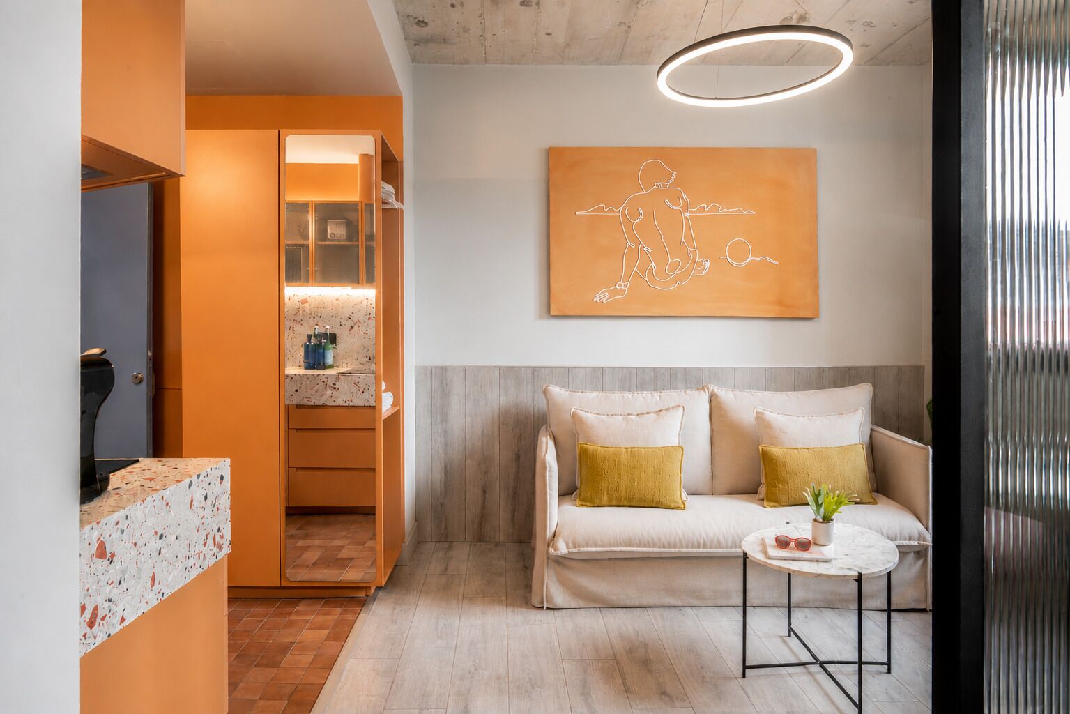A modern living room with a sofa, a small round table, and a wall-mounted artwork.