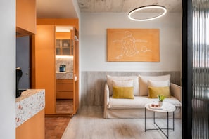 A modern living room with a sofa, a small round table, and a wall-mounted artwork. - Coeo Parras Design Apartments (Málaga)