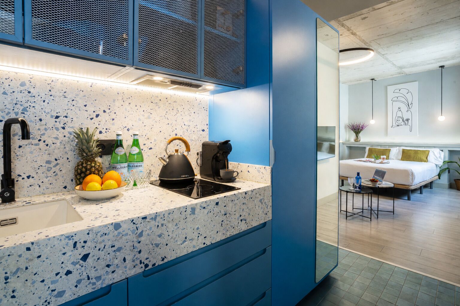 A modern kitchen with a speckled countertop, a kettle, and a coffee maker.